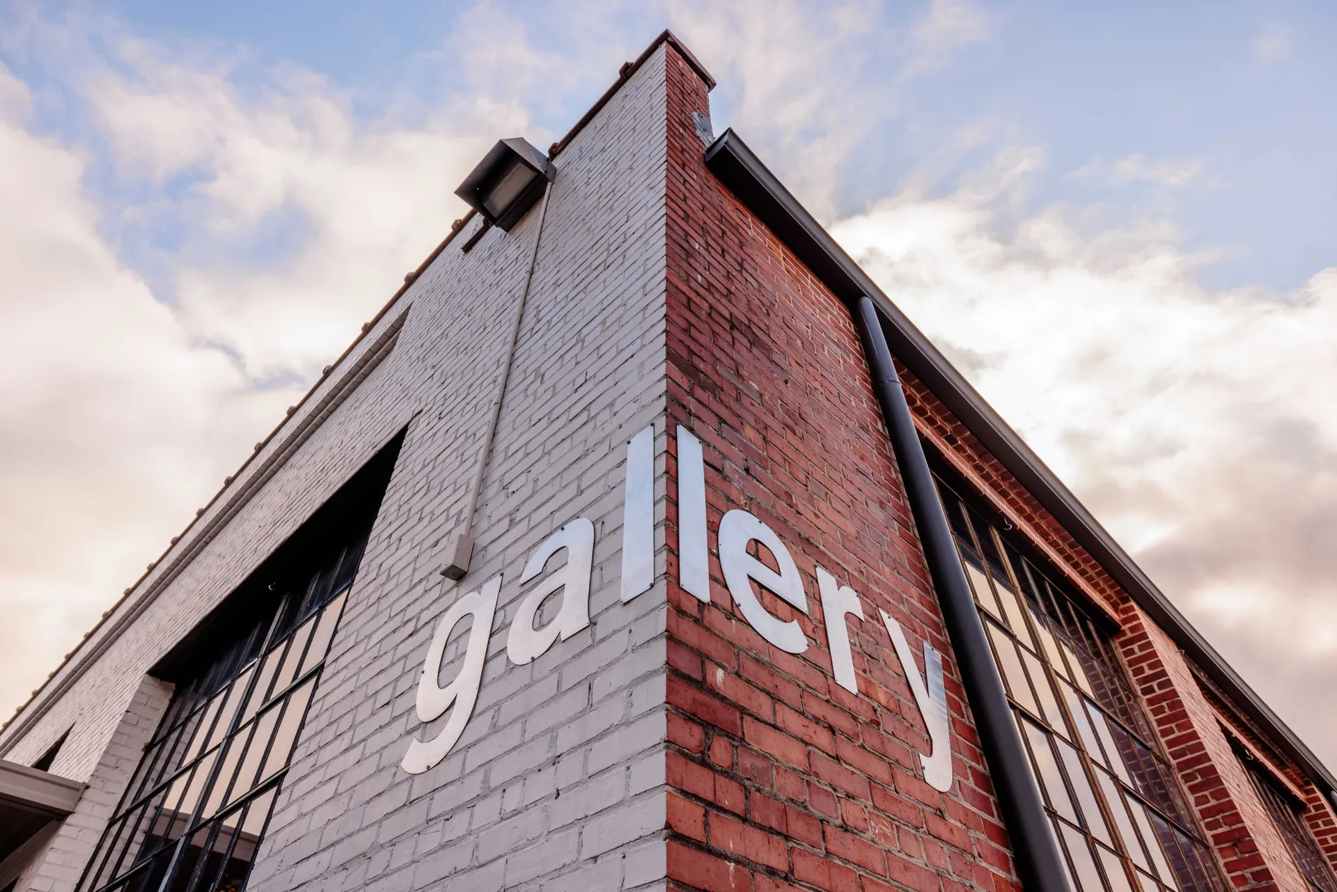 The brick corner of an event gallery venue under a soft evening sky.
