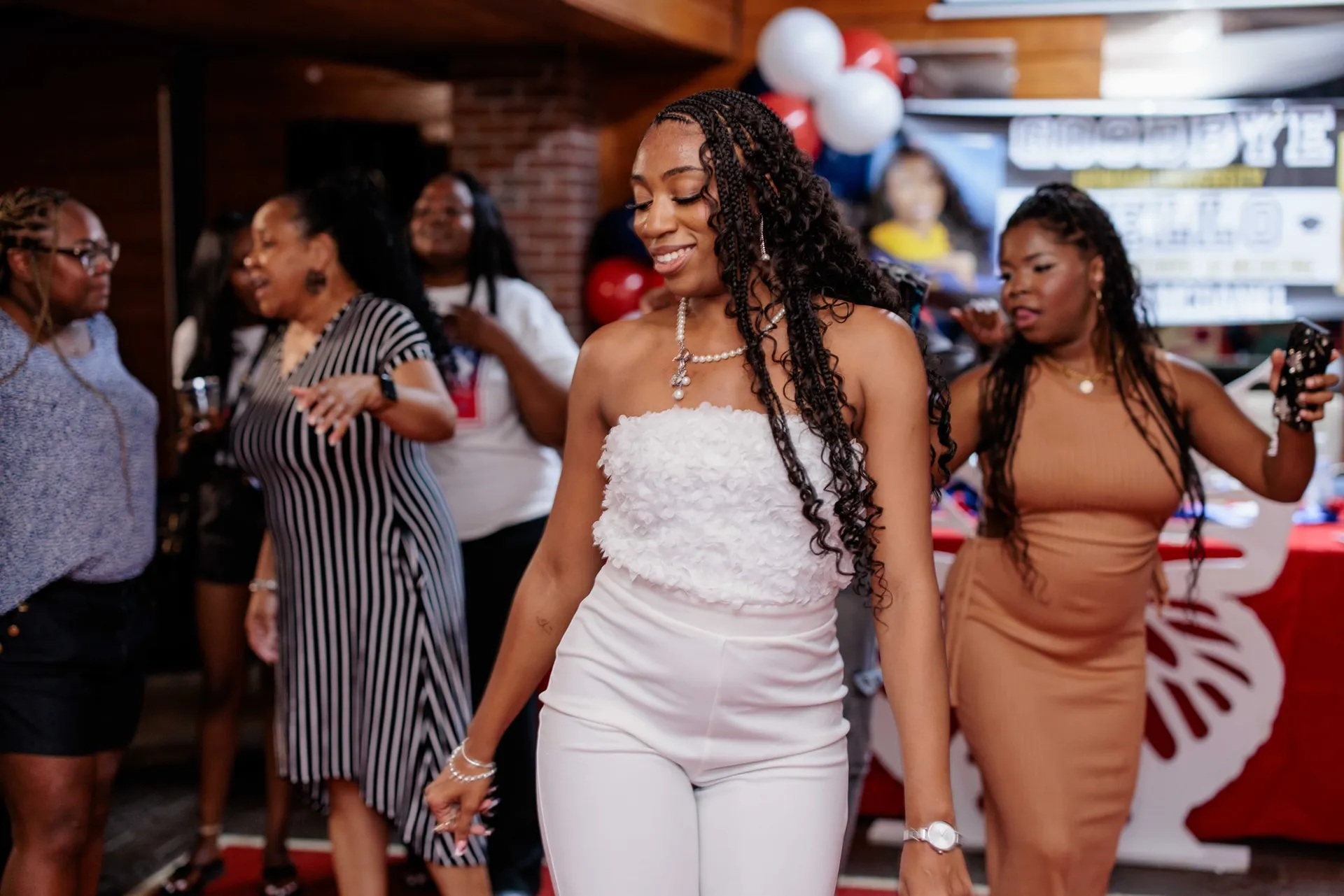The graduate in white dancing with friends and family at her graduation party.