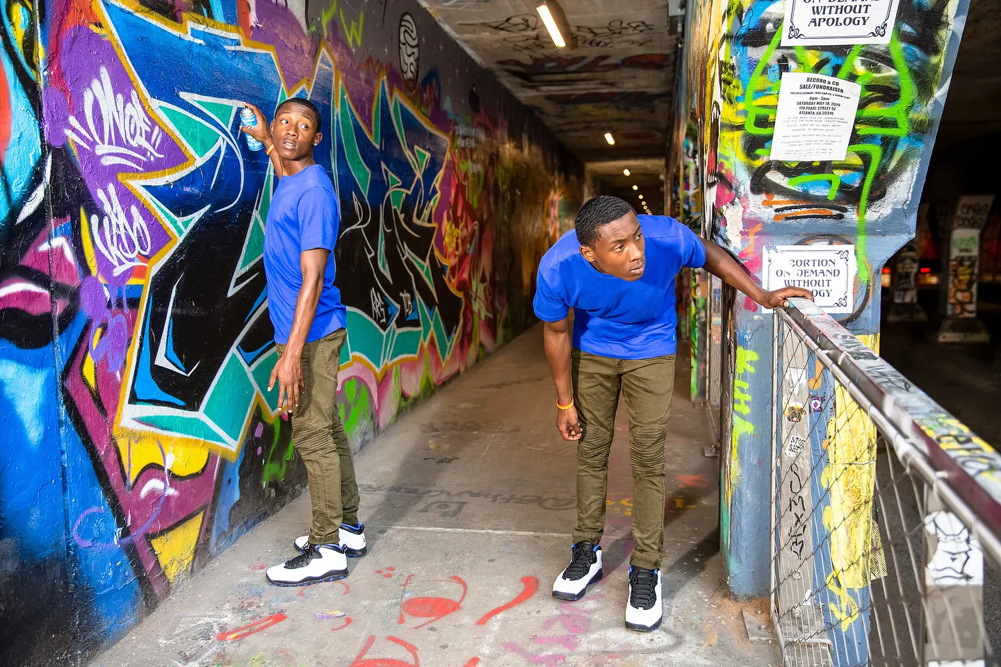 Two young men in blue tees among the graffiti inside Krog Street Tunnel in Atlanta.